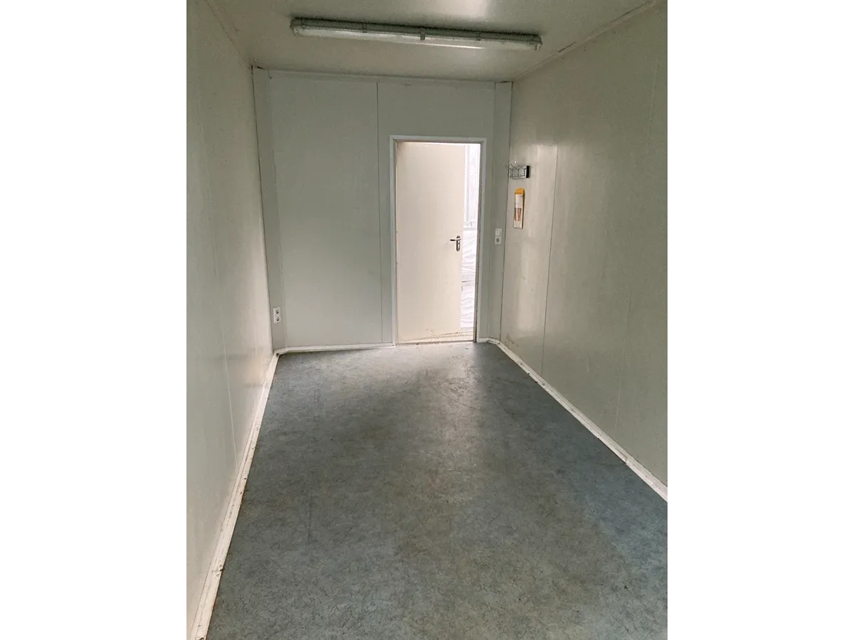 Gebrauchter 20 Fuß Bürocontainer Innenansicht mit weißer Eingangstür, Vinylboden und Deckenbeleuchtung