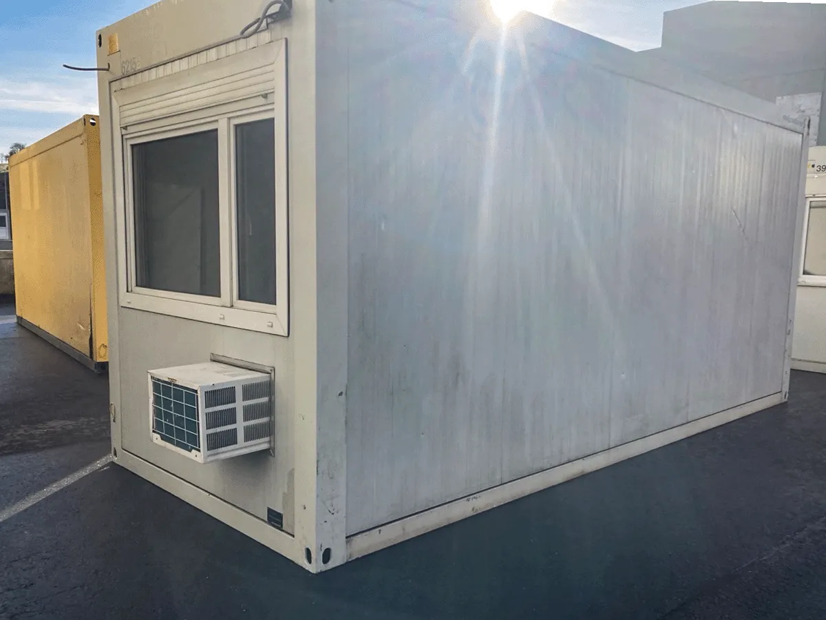 Außenansicht eines gebrauchten grauen Bürocontainers mit Fenster und Klimaanlage.