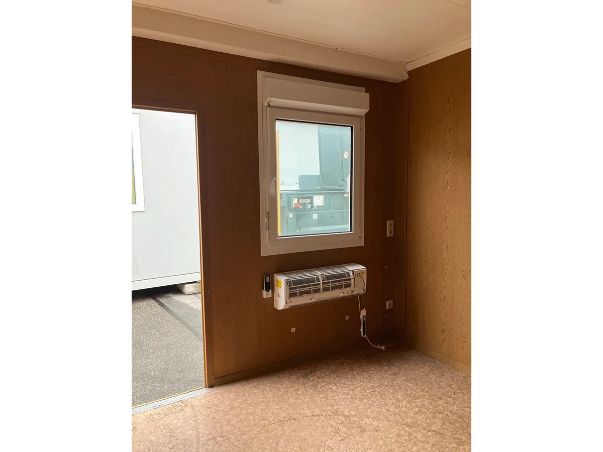 Gebrauchter 20 Fuß Bürocontainer Innenansicht mit Eingangstür, Deckenleuchte und offener Seitenfront – Blick zur Türseite