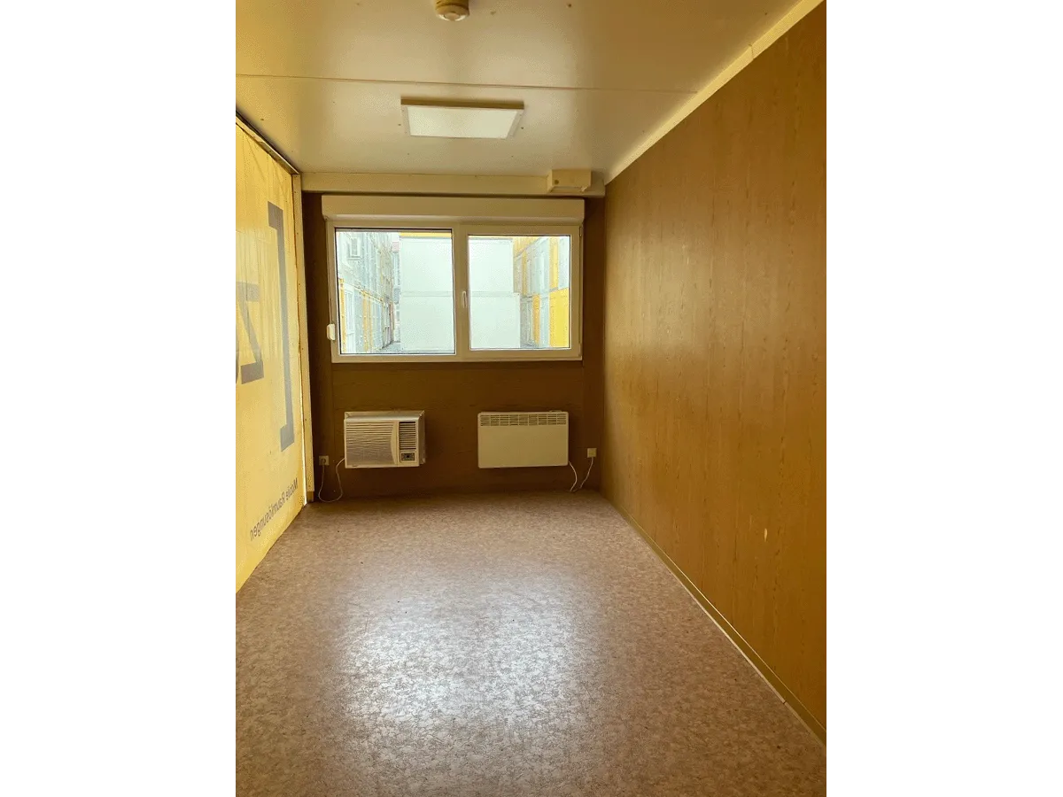 Gebrauchter 20 Fuß Bürocontainer Innenansicht mit großem Fenster, Klimagerät und Konvektorheizung – Blick zur Fensterseite