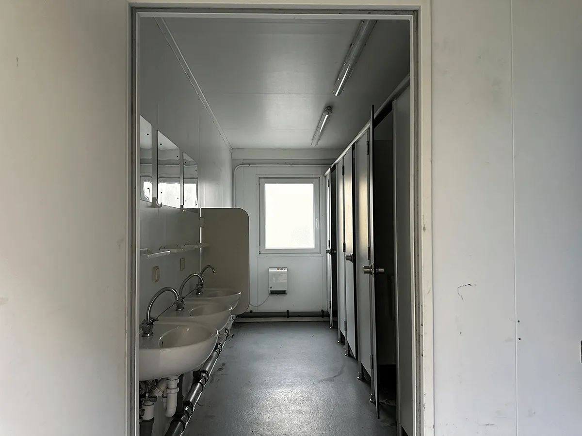 Innenansicht mit Waschbeckenreihe und Kabinen