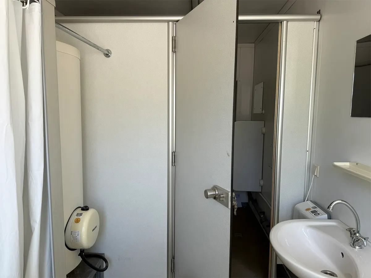 Gebrauchter Sanitärcontainer Innenansicht mit Waschbecken und Kabinentür