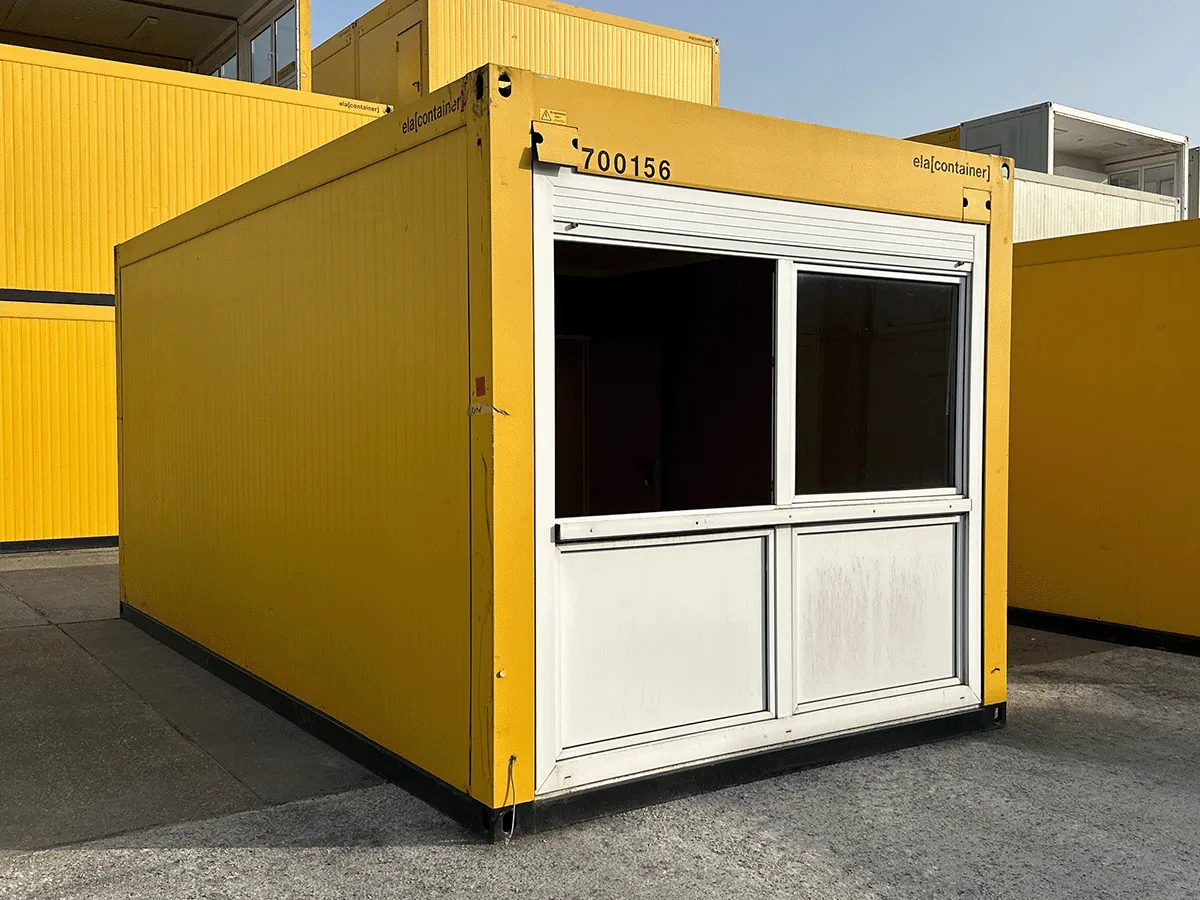 Außenansicht eines gebrauchten gelben Bürocontainers mit Doppel-Fenster und Rollladen auf einem Betriebshof.