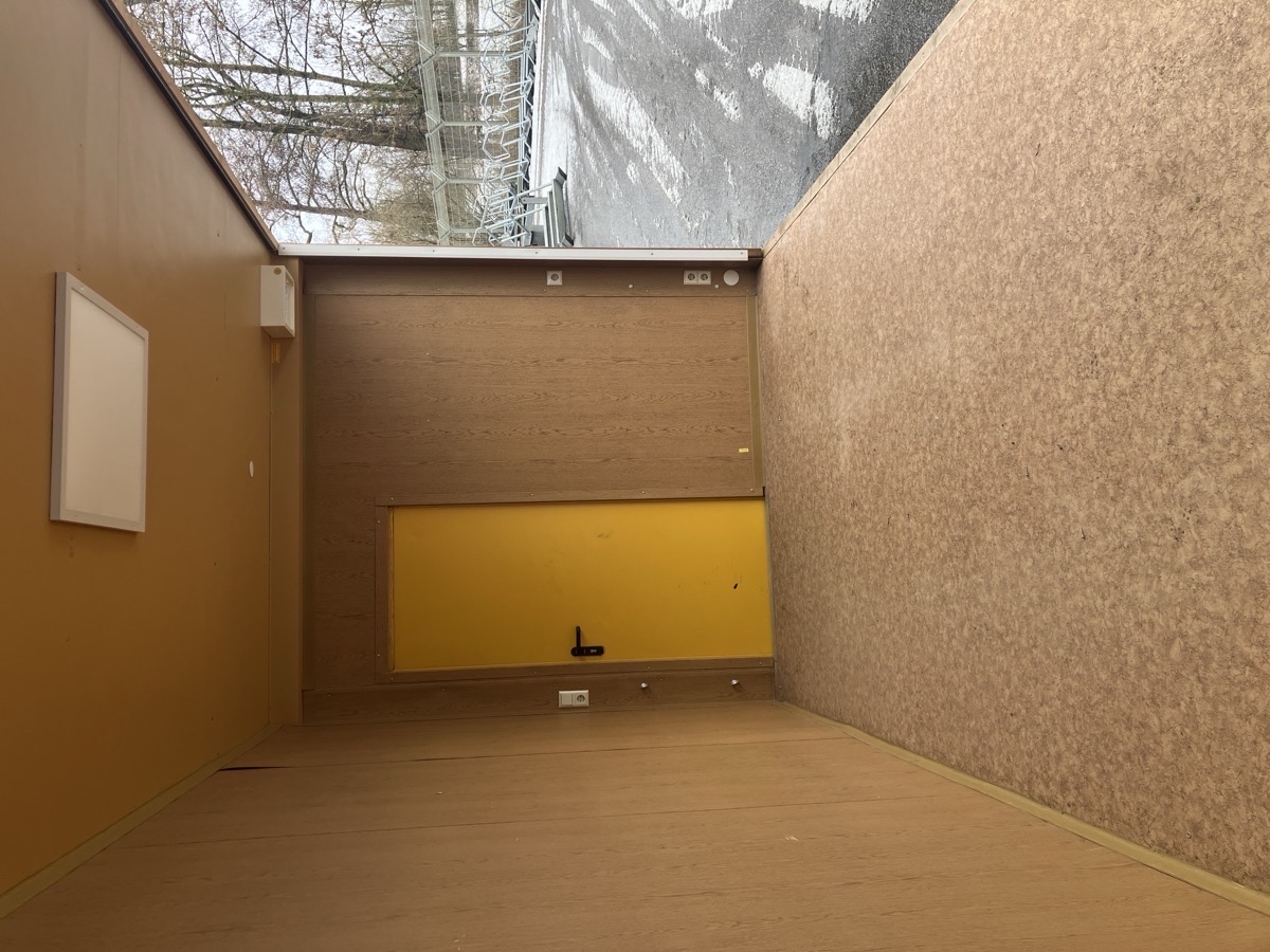 Gebrauchter 20 Fuß Bürocontainer Innenansicht mit gelber Tür, Steckdose und OSB-Wandverkleidung – Blick von oben zur Türseite