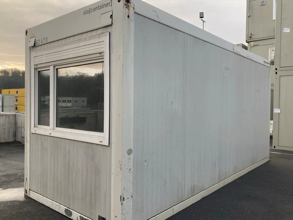 Rückansicht eines gebrauchten grauen Bürocontainers mit geschlossener Eingangstür.