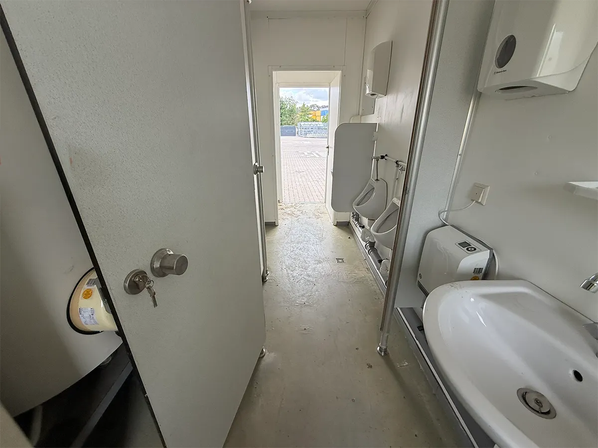 Gebrauchter Sanitärcontainer Innenansicht mit Waschbecken und offener Tür