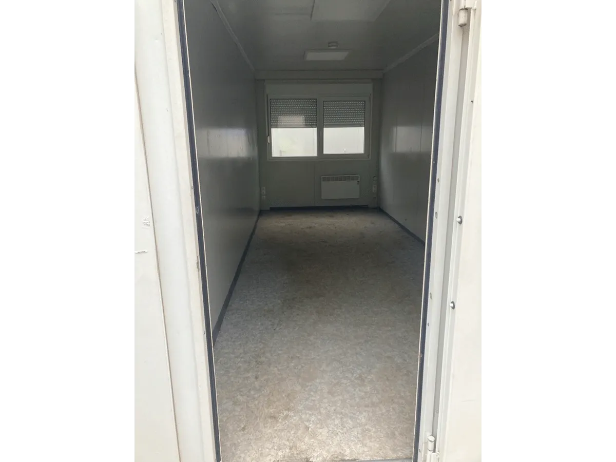 Gebrauchter Bürocontainer Innenansicht mit Fenster Heizung und Vinylboden durch offene Tür