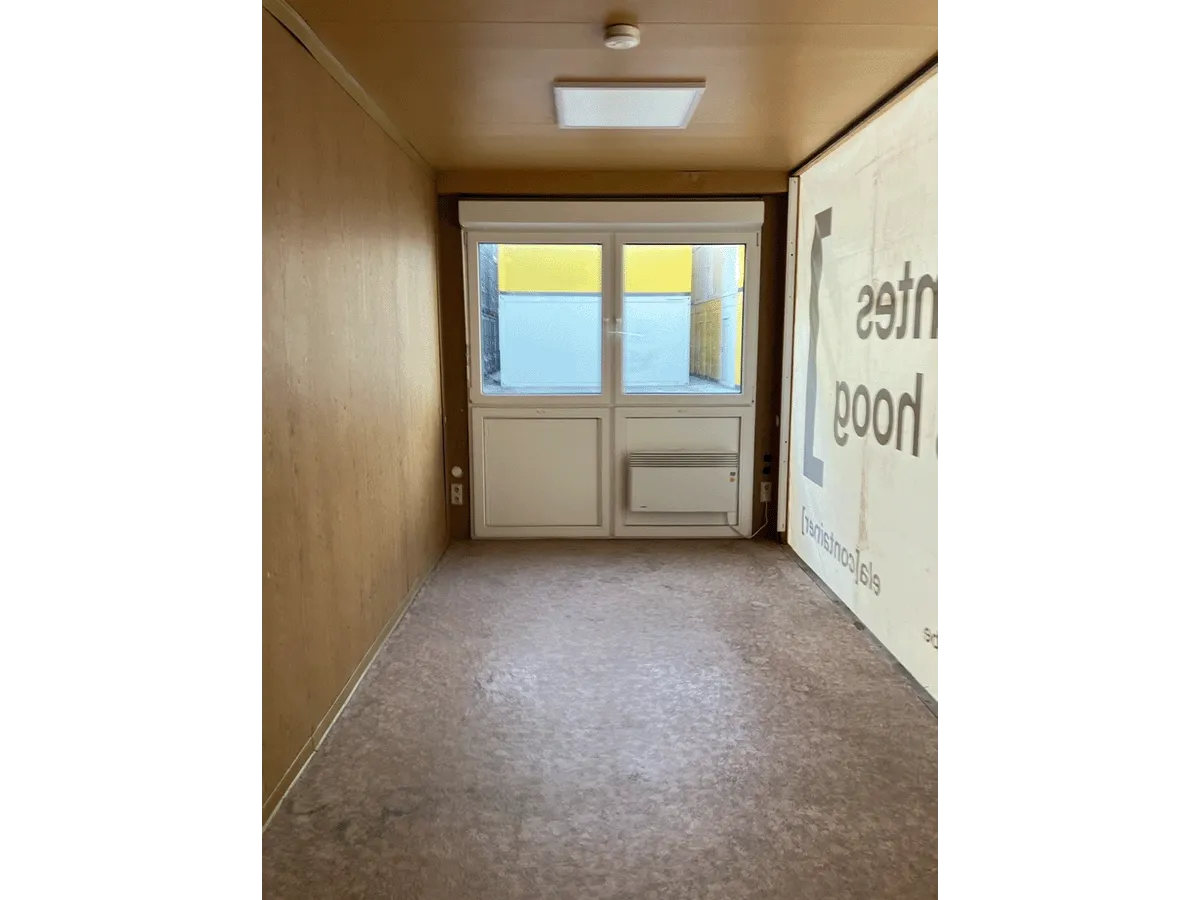 Gebrauchter 20 Fuß Bürocontainer Innenansicht mit Fenster, Heizkörper und Deckenbeleuchtung – Blick Richtung Eingan