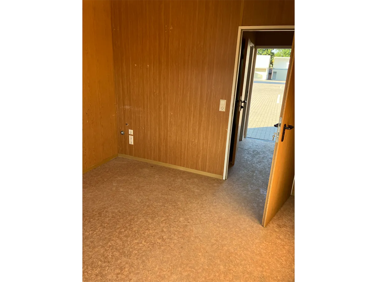 Gebrauchter Bürocontainer Innenansicht mit Holzpaneelen und offener Tür