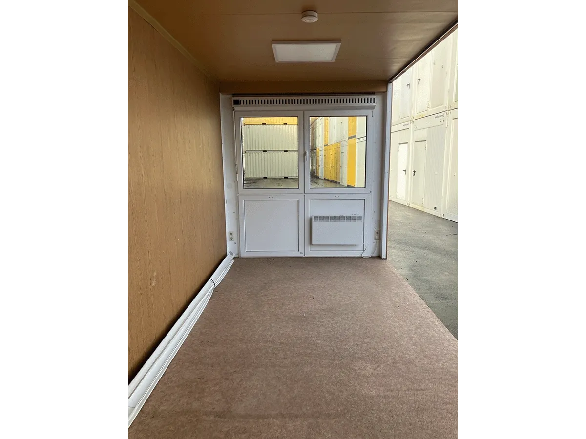 Gebrauchter 20 Fuß Bürocontainer Innenansicht mit Glastür, Heizkörper und Bewegungsmelder – Blick Richtung Eingang