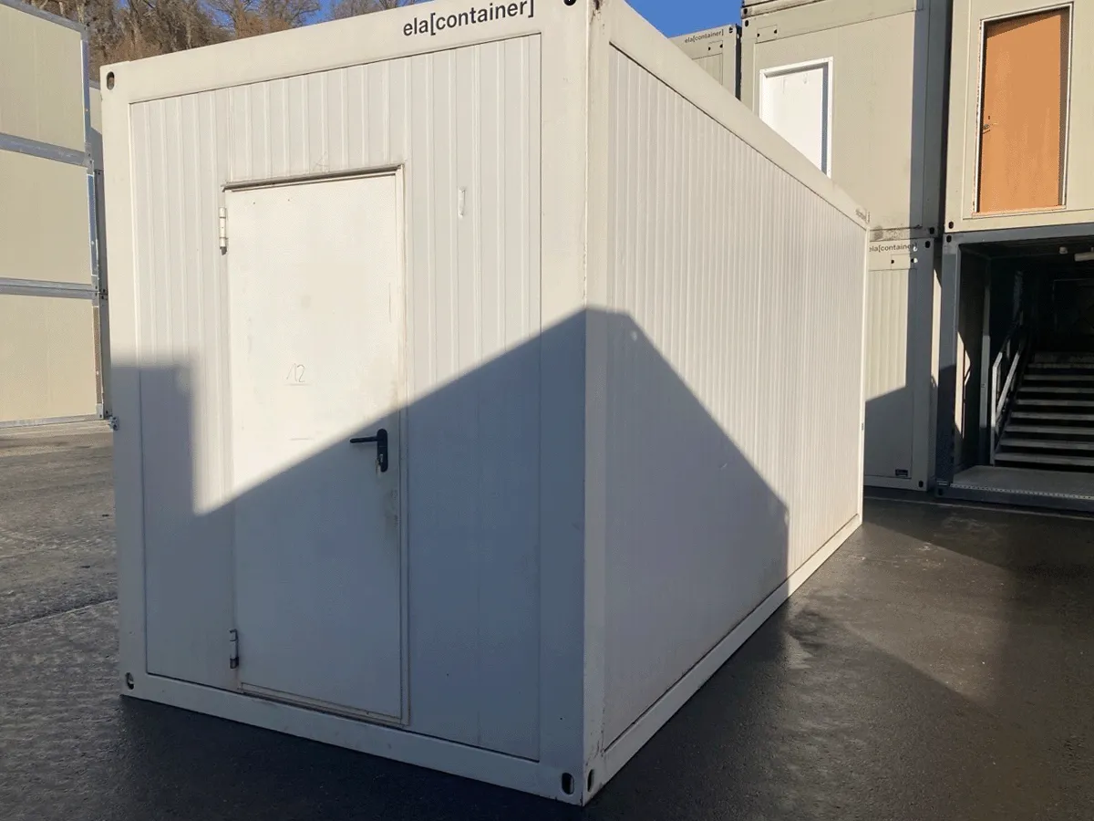 Außenansicht eines gebrauchten grauen Bürocontainers mit geschlossener Eingangstür auf einem Stellplatz.