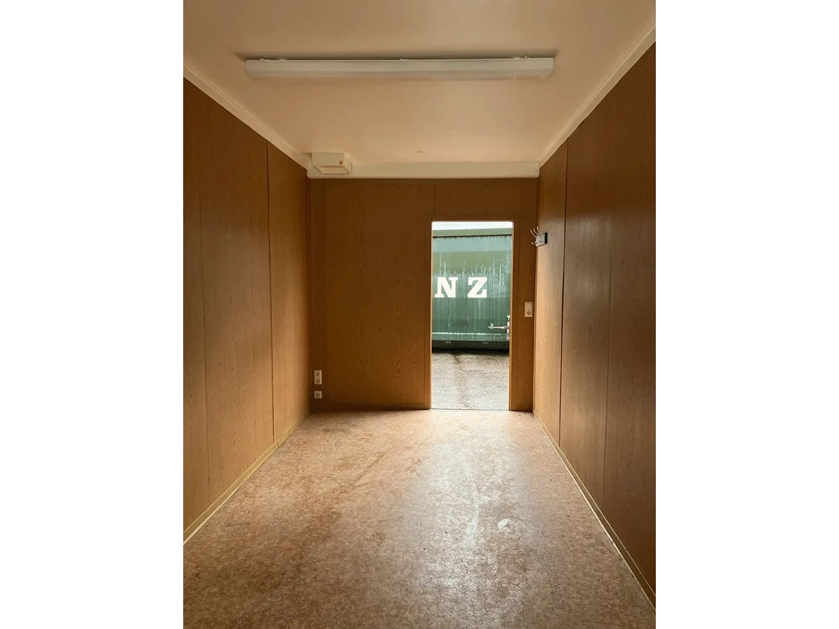 Gebrauchter Bürocontainer Innenraum mit Holzwandverkleidung offener Tür und Deckenleuchte