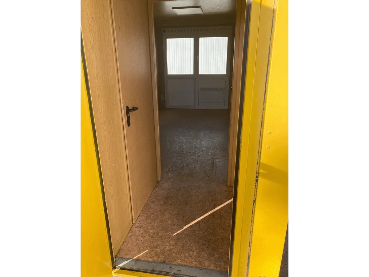 Gebrauchter 20 Fuß Bürocontainer mit offener gelber Eingangstür und Blick in den Innenraum mit Fenster und Deckenleuchte
