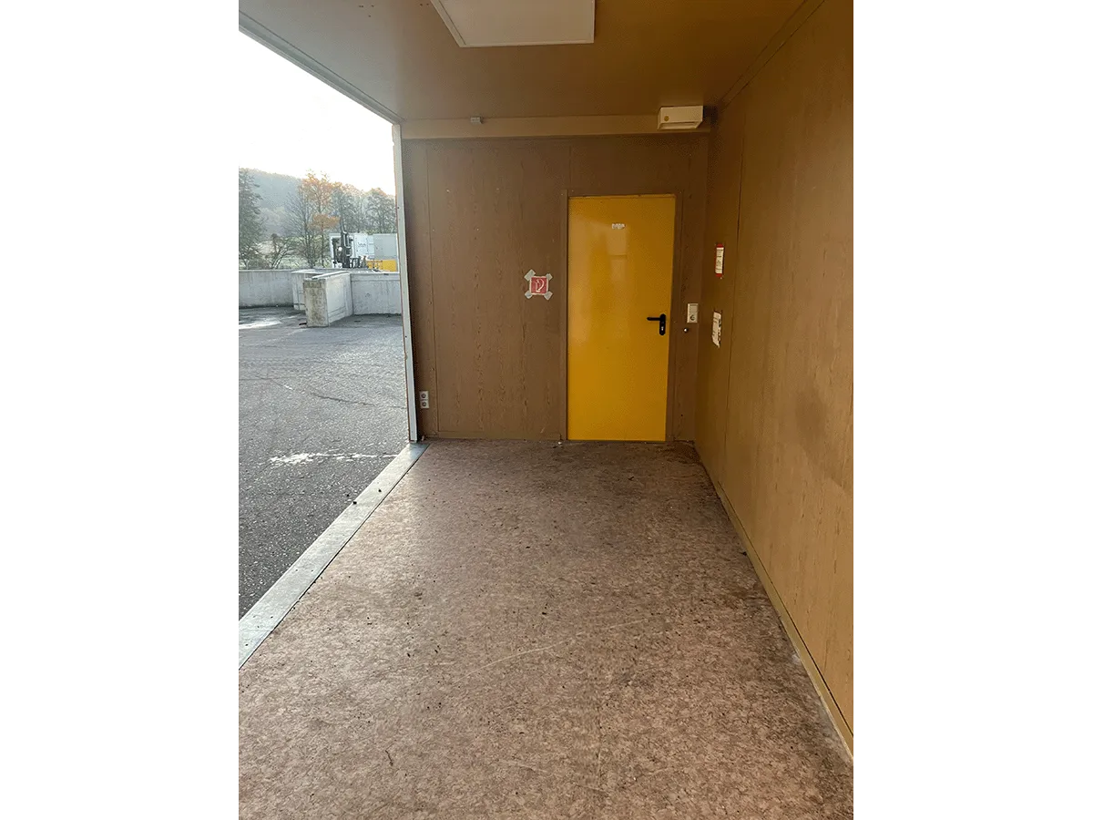 Gebrauchter 20 Fuß Bürocontainer Innenansicht mit gelber Tür, OSB-Wandverkleidung und Bodenbelag