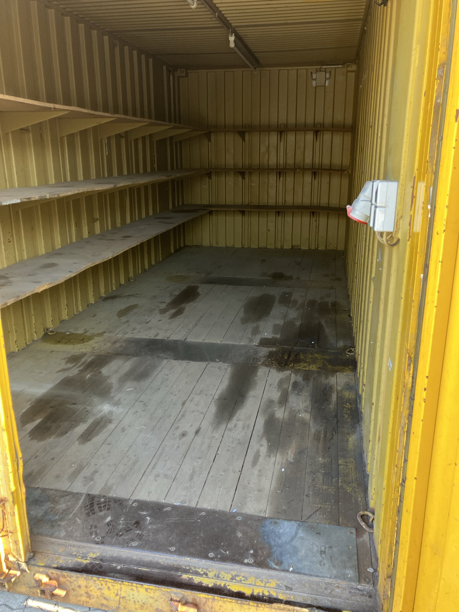 Gebrauchter gelber Container von innen mit Holzboden und Regalen an der Seitenwand