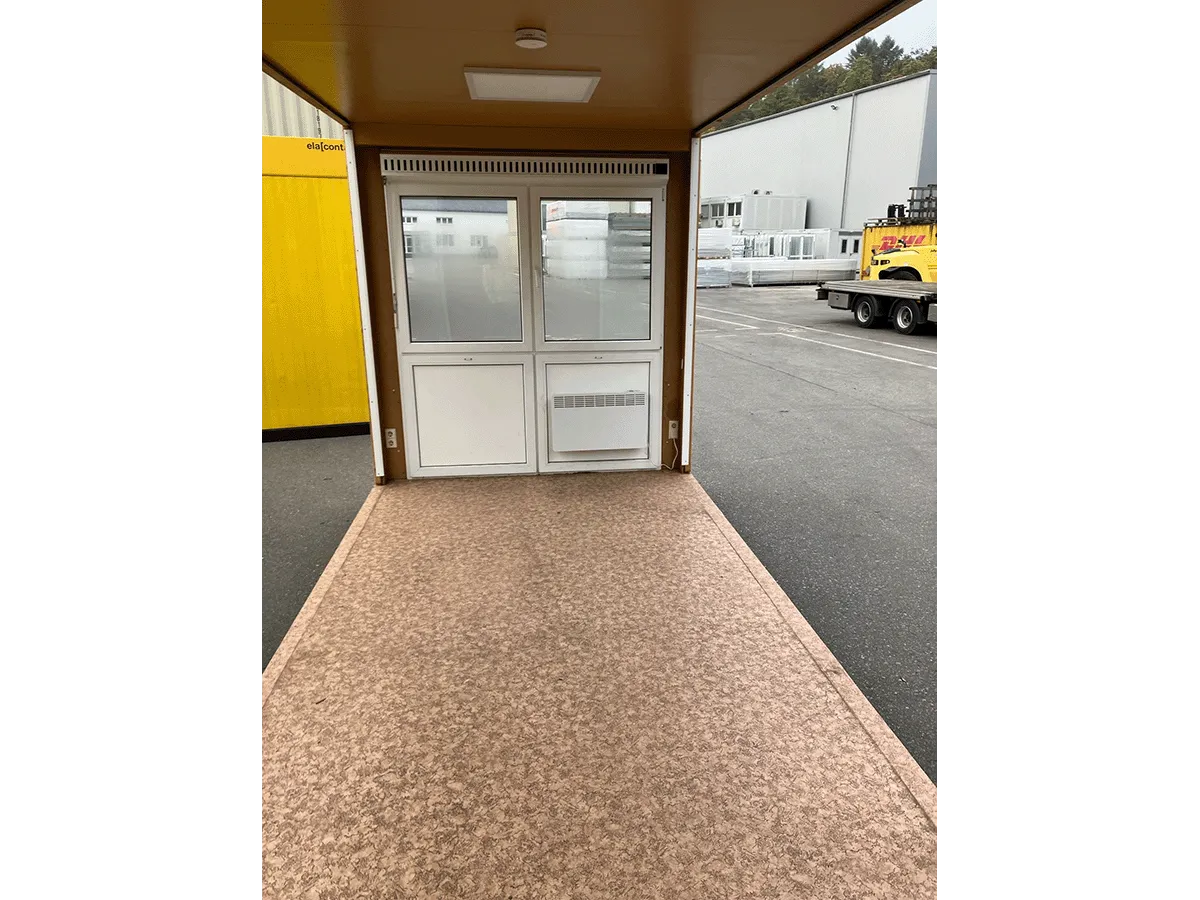 Gebrauchter 20 Fuß Bürocontainer Innenansicht mit Glastür, Heizkörper und Bewegungsmelder – Blick Richtung Eingang