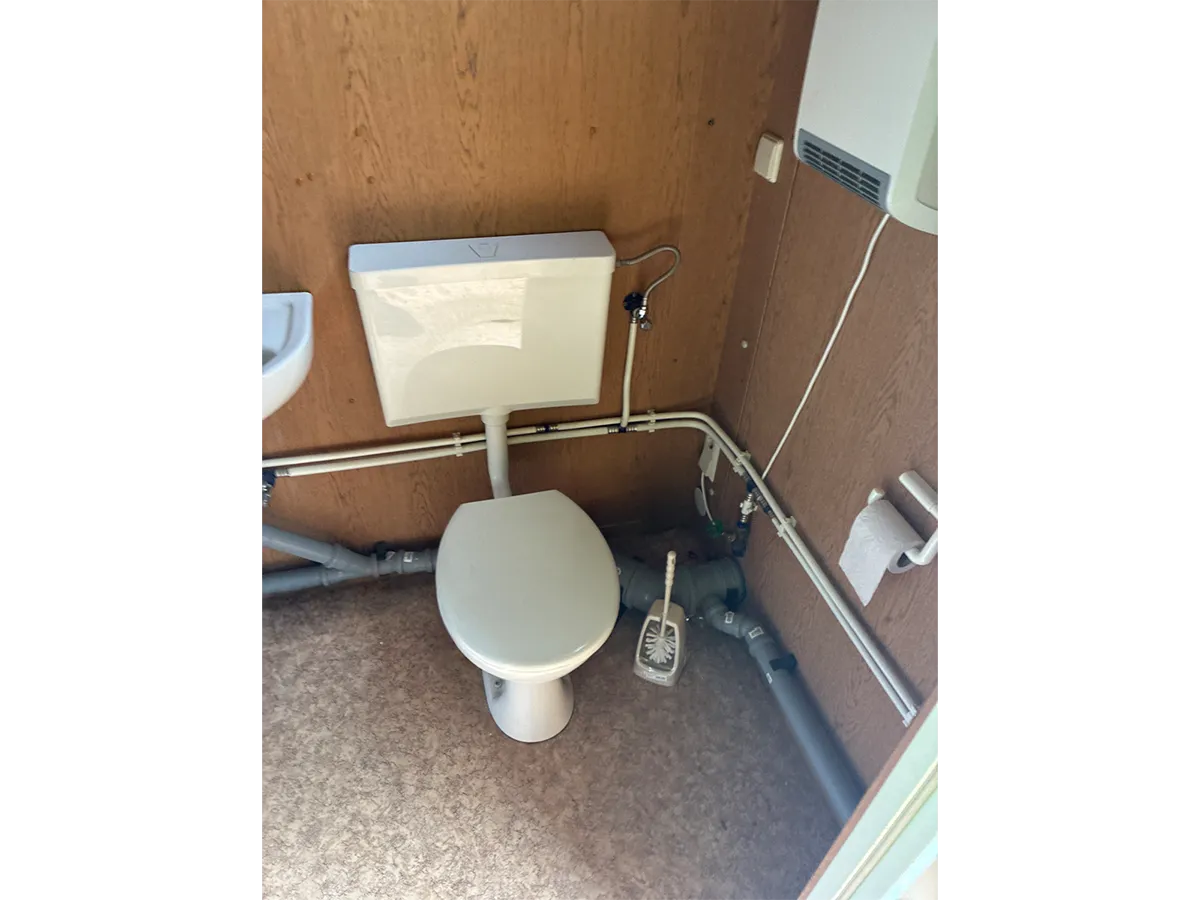 Gebrauchter Bürocontainer Innenansicht mit WC und Holzpaneelen