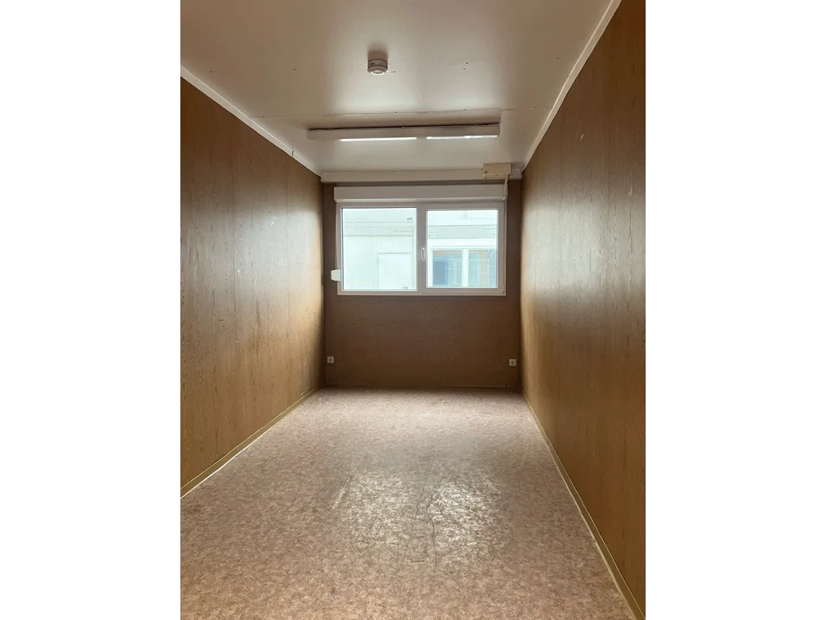 Gebrauchter 20 Fuß Bürocontainer Innenansicht mit Fenster, Neonbeleuchtung und Bewegungsmelder – Blick Richtung Fensterseite