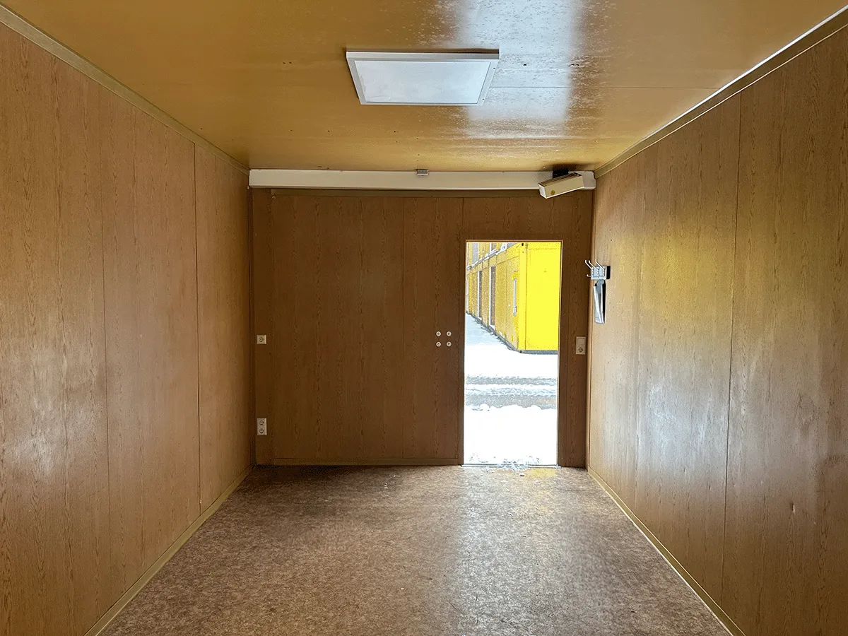 Gebrauchter 20 Fuß Bürocontainer Innenansicht mit offener Doppeltür, Steckdosen und Deckenleuchte – Blick zum Ausgang
