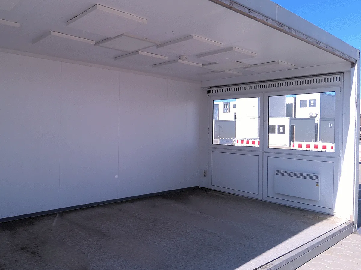 Innenansicht eines leeren grauen 20 Fuß Bürocontainers (3m Breite) mit Doppel-Fenster, Heizung und hellem Bodenbelag.