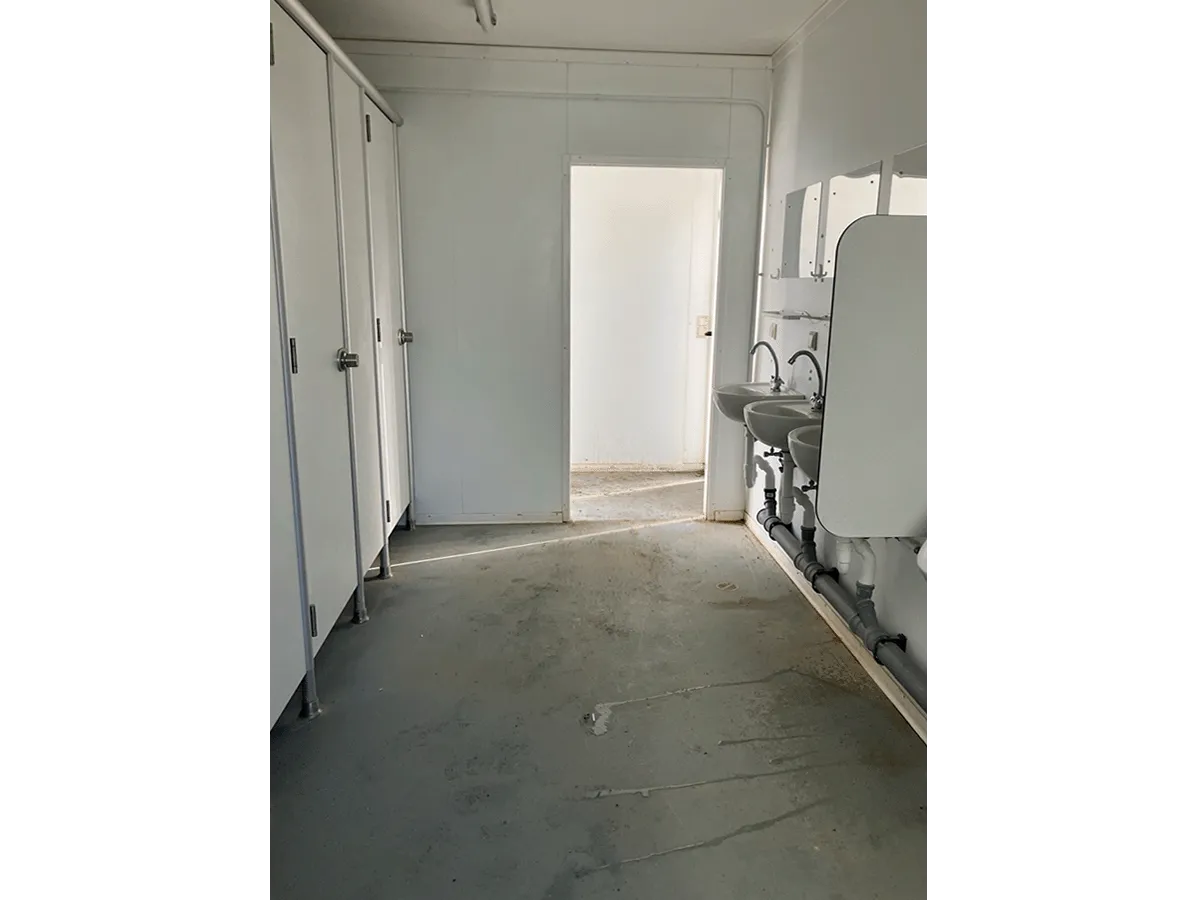 Innenansicht mit Toilettenkabinen und Waschbereich