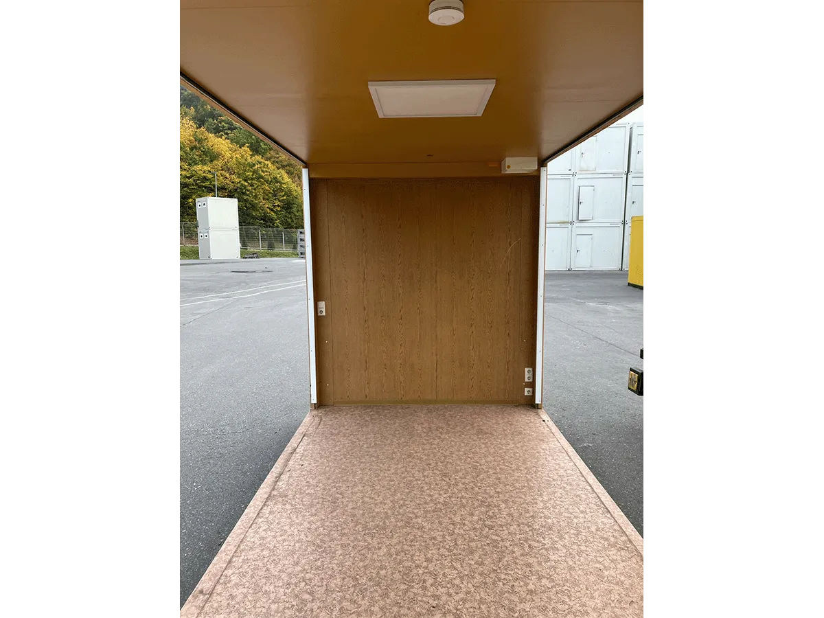 Gebrauchter 20 Fuß Bürocontainer Innenansicht mit Eingangstür, Deckenleuchte und offener Seitenfront – Blick zur Türseite