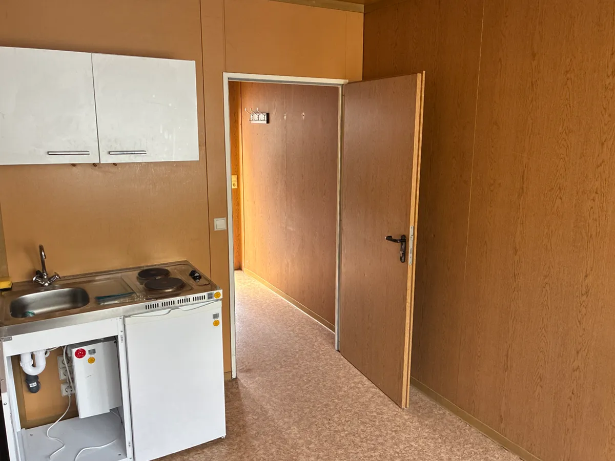 Gebrauchter Bürocontainer Innenansicht mit Kleinküche und offener Tür