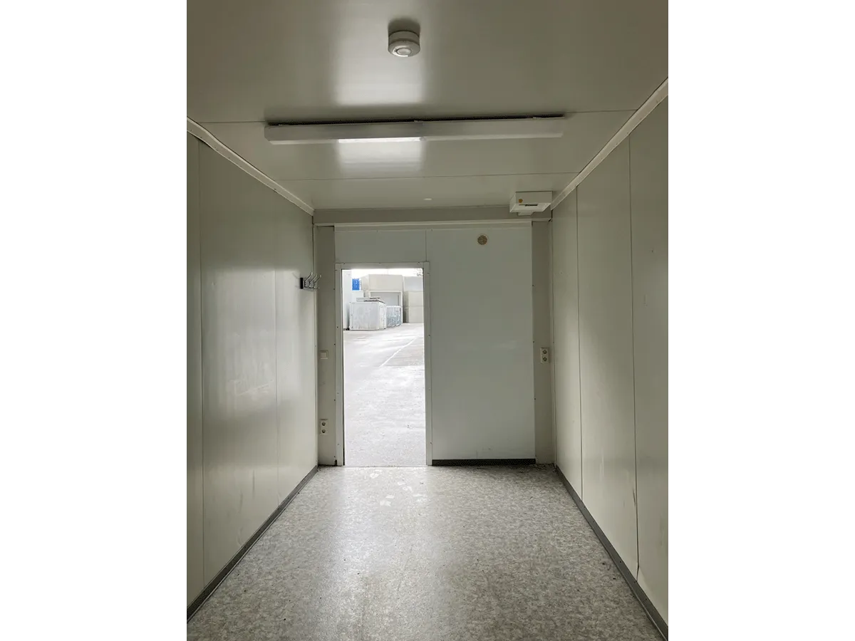 Gebrauchter Bürocontainer Innenraum mit offener Eingangstür Deckenleuchte und Steckdosen