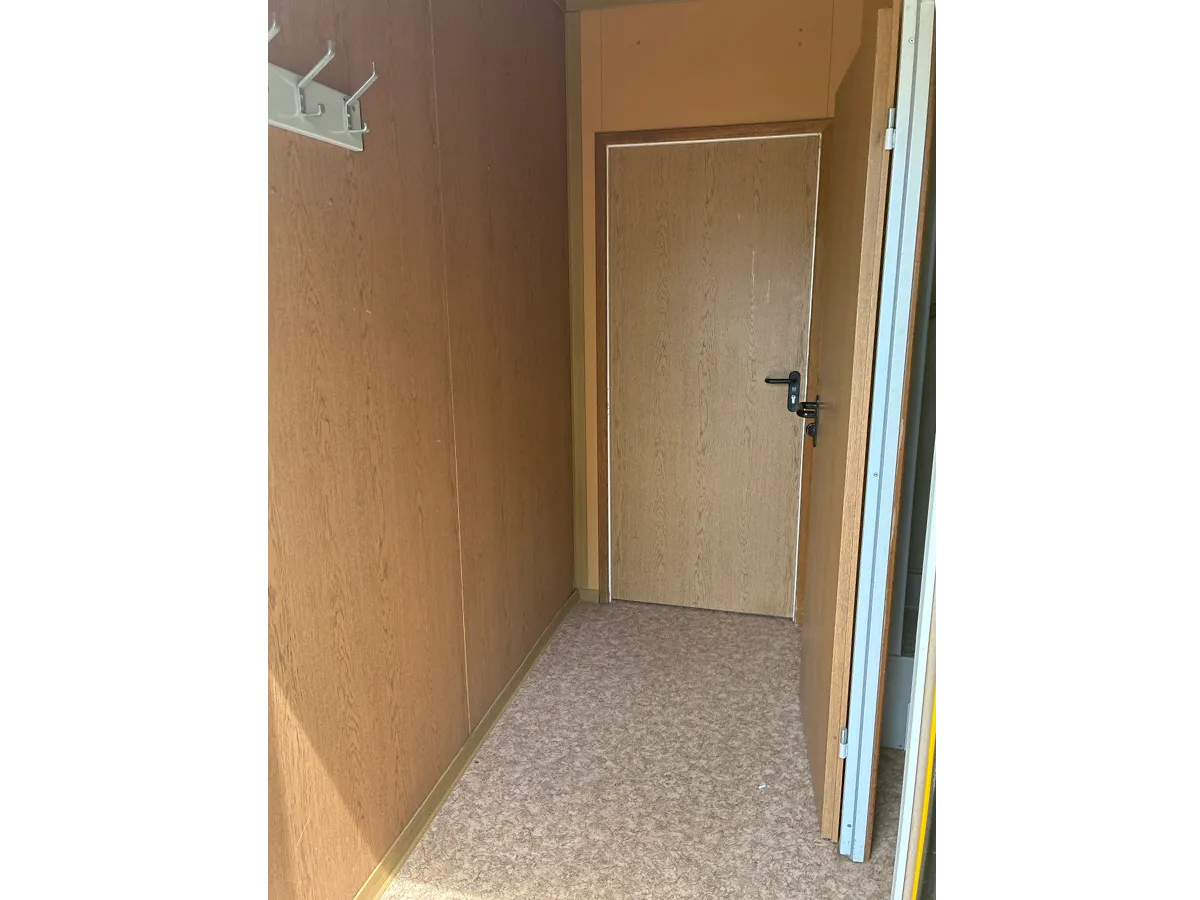 Gebrauchter Bürocontainer Innenansicht mit Holzpaneelen und Tür