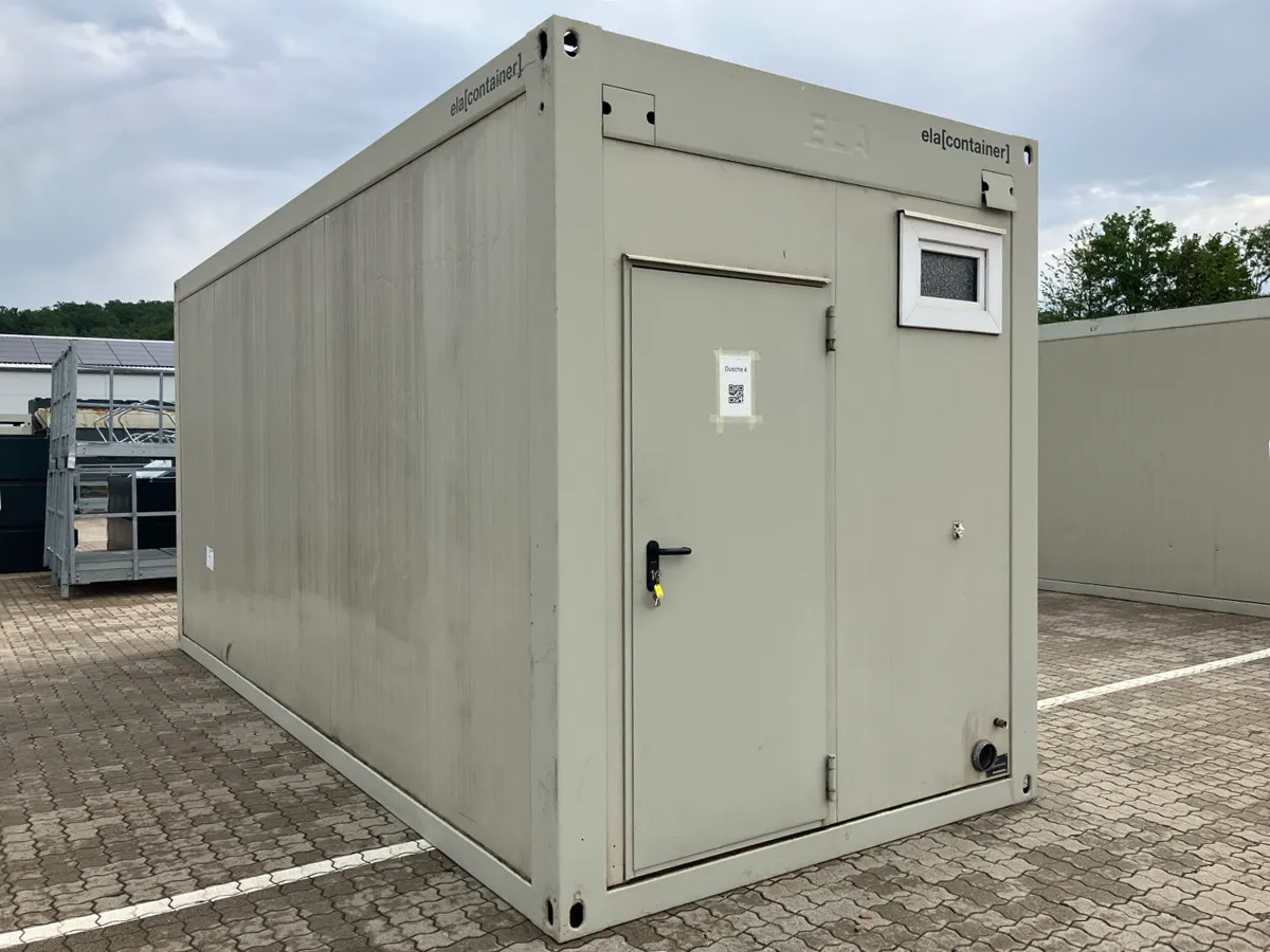 Gebrauchter WC-Container hellgrau mit Außentür und kleinem Fenster, Außenansicht