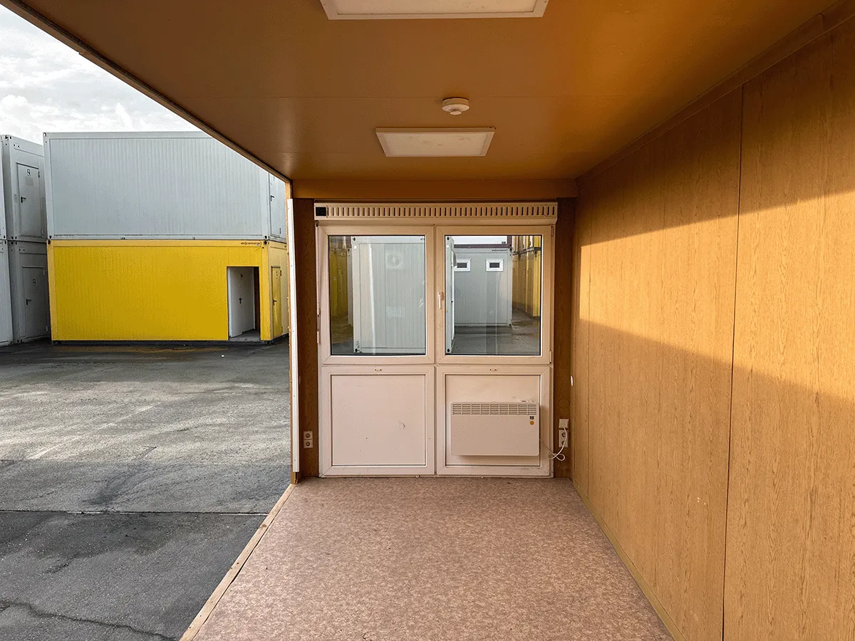 Gebrauchter 20 Fuß Bürocontainer Innenansicht mit Glastür, Heizkörper und OSB-Wandverkleidung – Blick Richtung Eingang