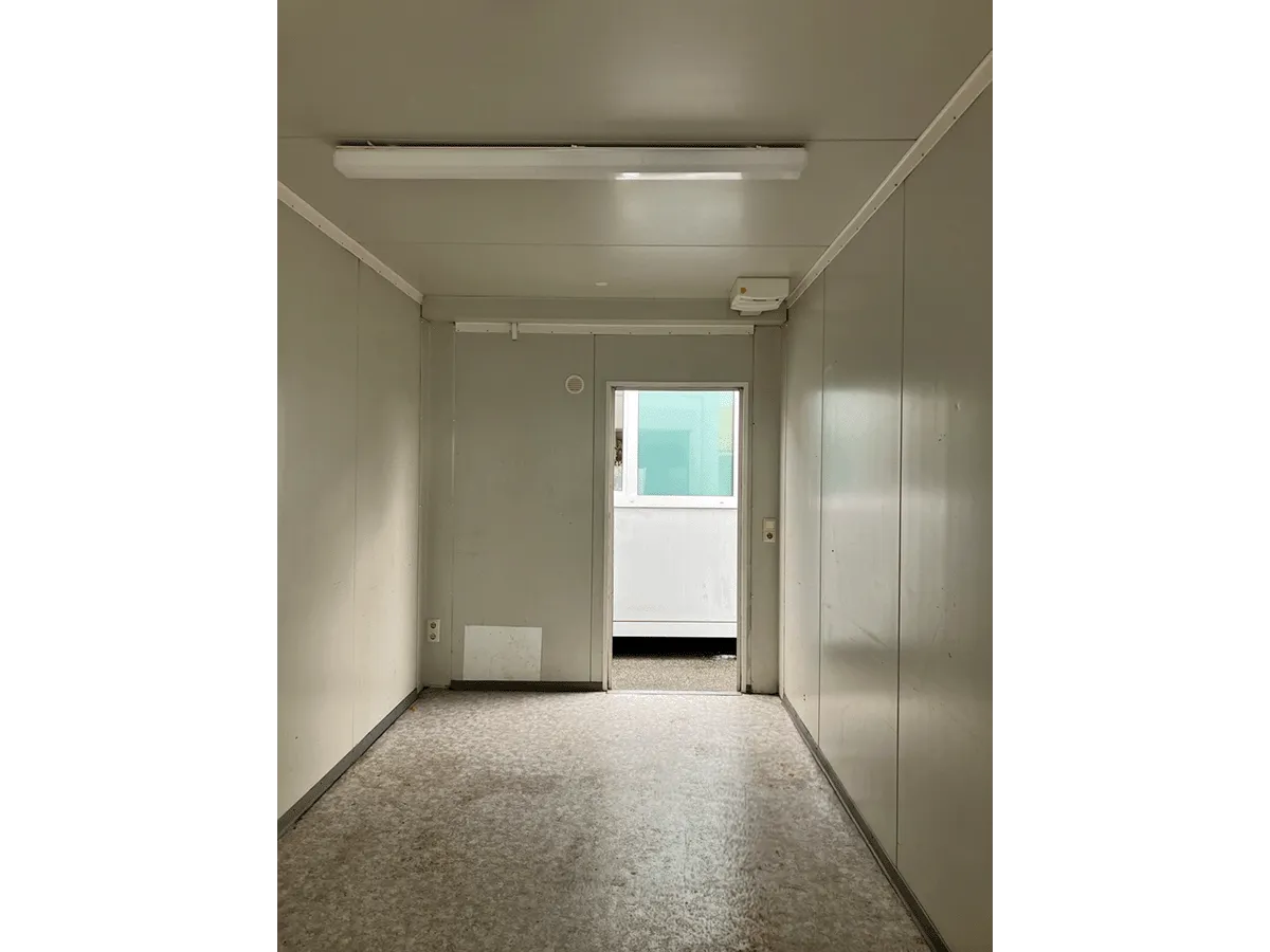 Gebrauchter Bürocontainer Innenraum mit offener Eingangstür Deckenleuchte und Vinylboden