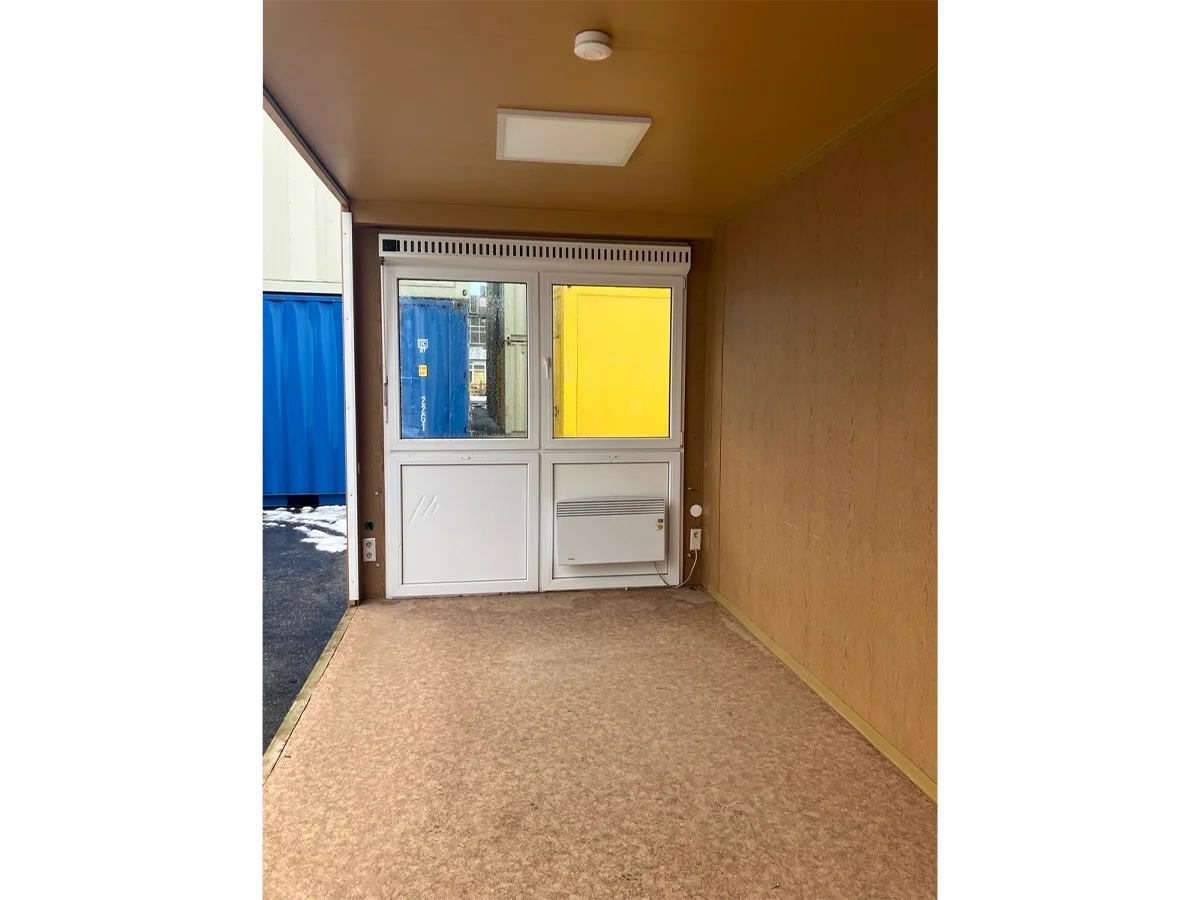 Gebrauchter 20 Fuß Bürocontainer Innenansicht mit Glastür, Bewegungsmelder und Deckenleuchte – Blick Richtung Eingang