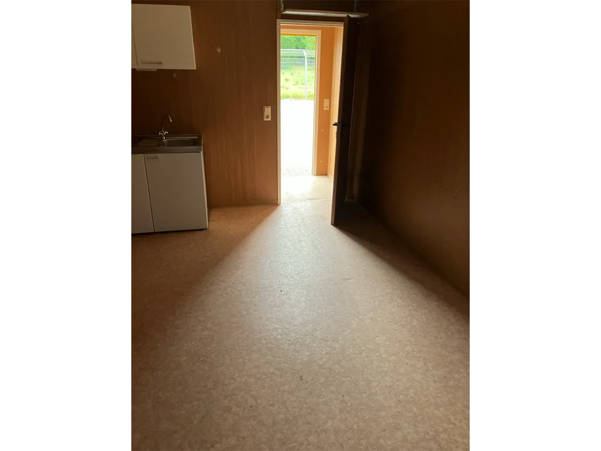 Gebrauchter Bürocontainer Innenansicht mit Holzpaneelen und offener Tür
