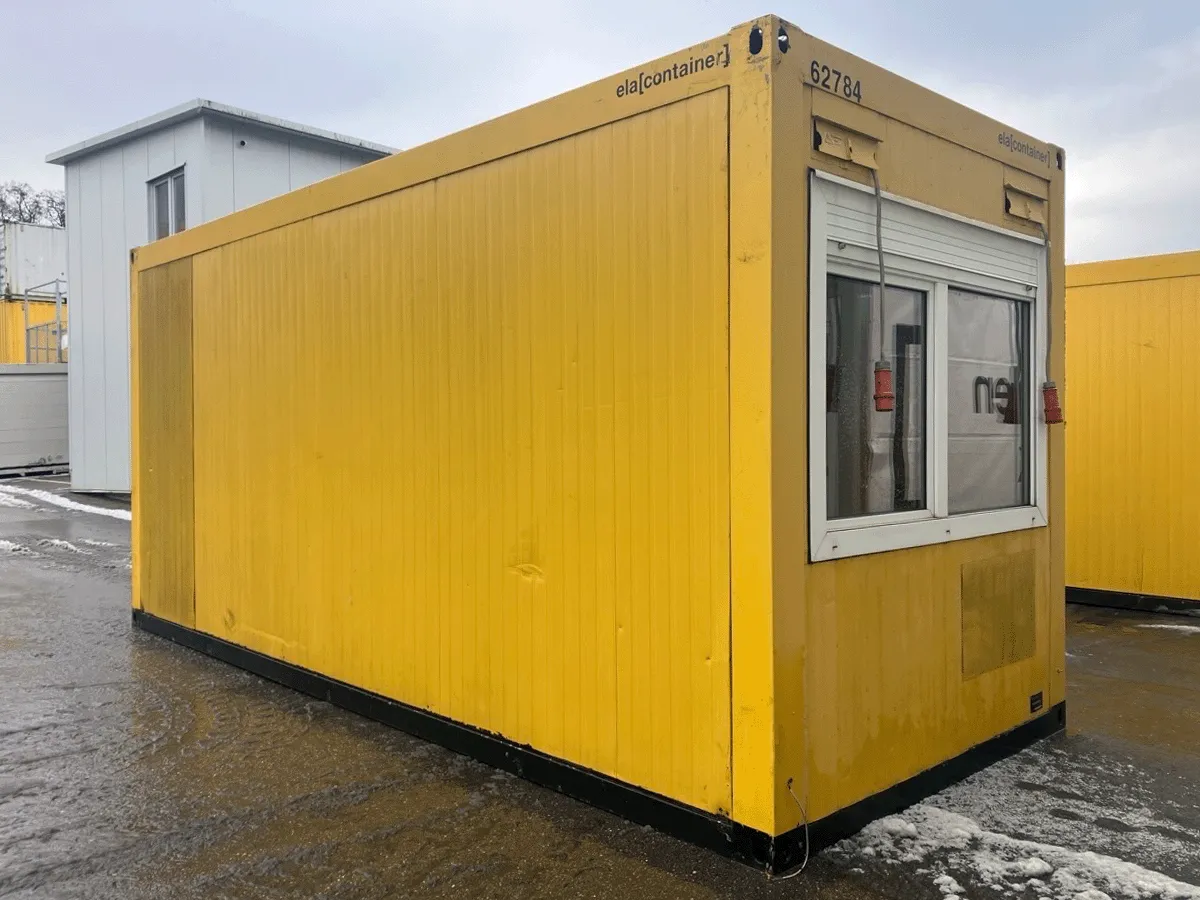 Außenansicht eines gebrauchten grauen Bürocontainers mit Fenster und Rollladen auf einem Betriebshof.