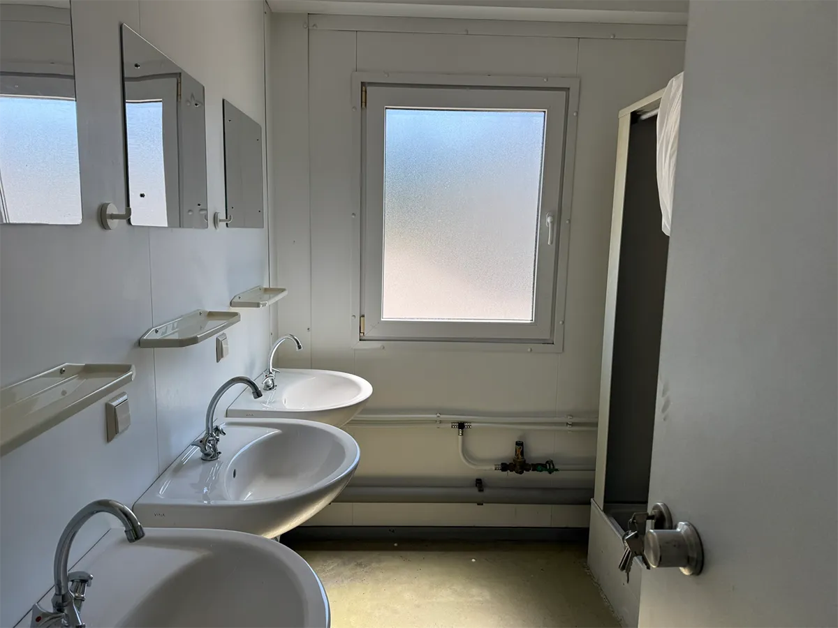 Gebrauchter Sanitärcontainer Innenansicht mit Waschbecken, Spiegel und Fenster