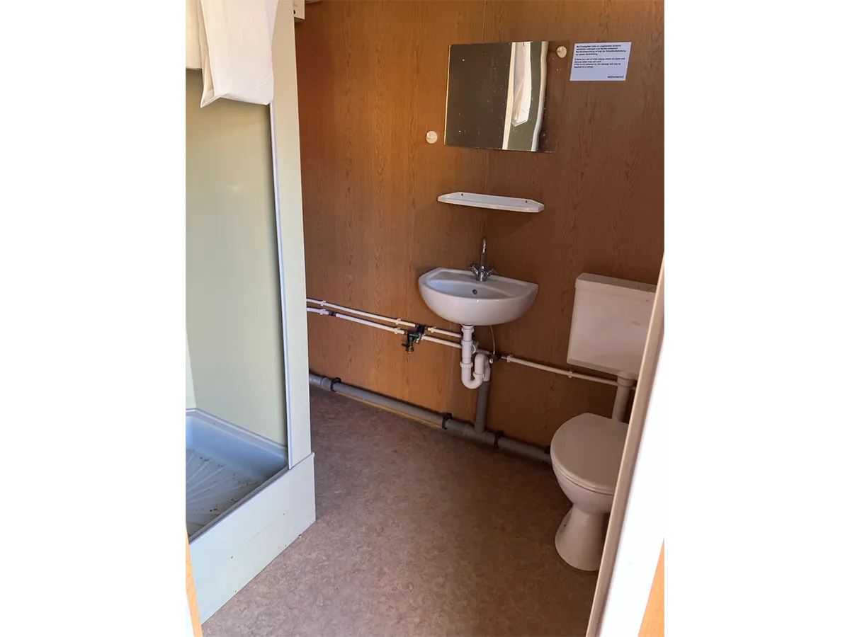 Gebrauchter Bürocontainer Innenansicht mit WC, Waschbecken und Spiegel