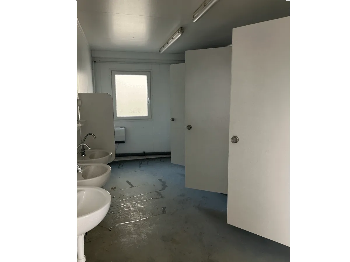 Innenraum mit Waschbecken und offenen Kabinentüren