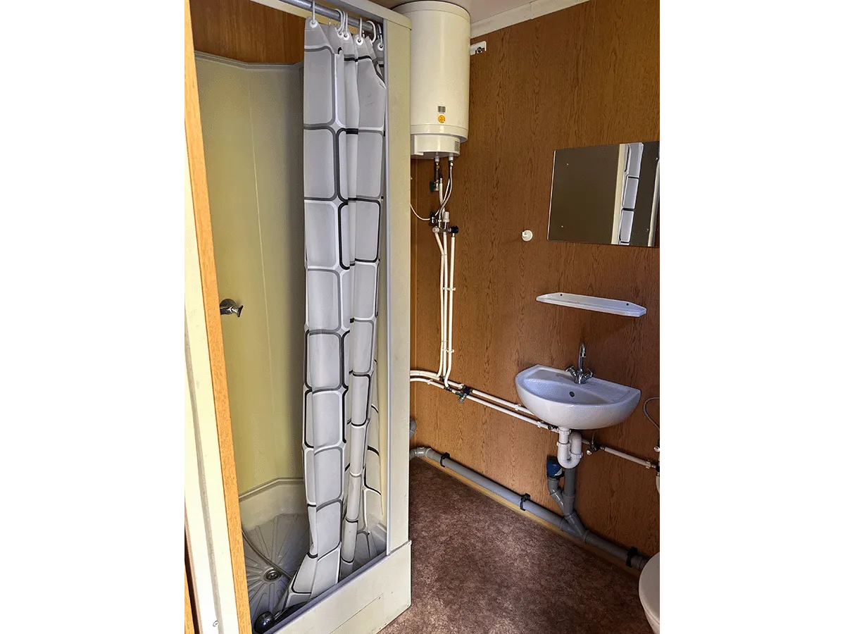 Innenansicht eines gelben Bürocontainers mit Fokus auf die Deckenbeleuchtung und den hellen Bodenbelag.