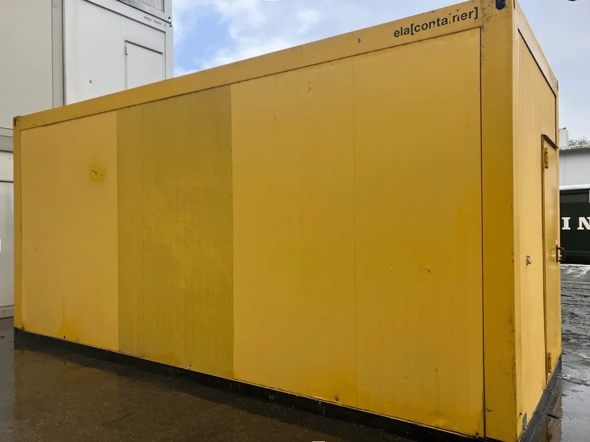 Rückansicht des gelben Bürocontainers mit geschlossener weißer Eingangstür auf einem asphaltierten Platz.