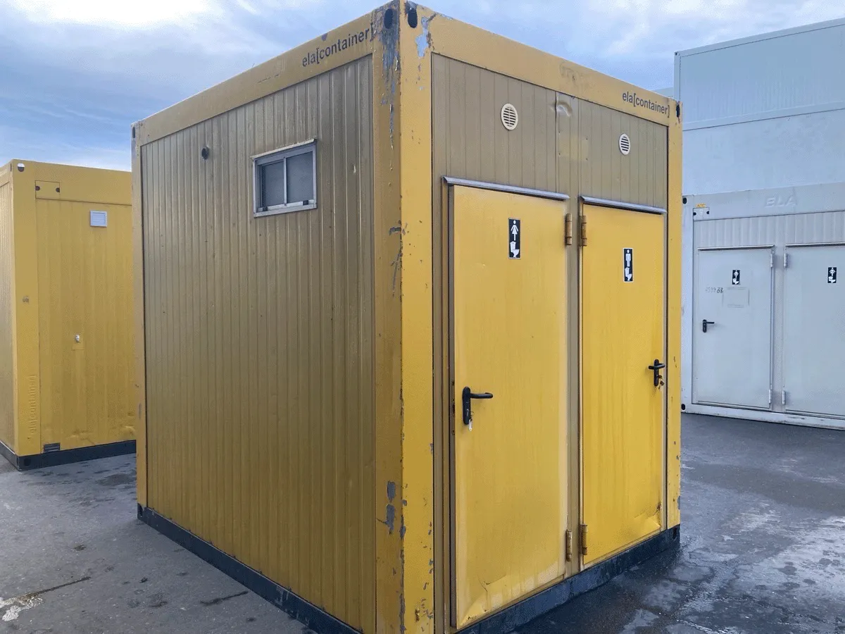 Gelber Sanitärcontainer mit zwei Toilettüren auf Baustelle