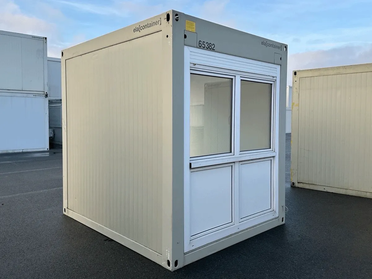 Außenansicht eines gebrauchten grauen Bürocontainers mit Fenster und geschlossenem Rollladen auf einem Betriebsgelände.