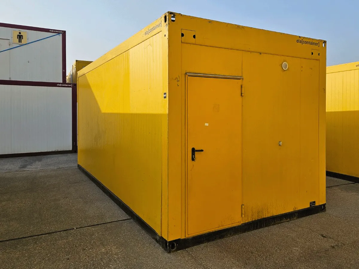 Außenansicht eines gebrauchten gelben Bürocontainers in Sonderbreite (3m) mit Fenster und Rollladen auf einem Lagerplatz.