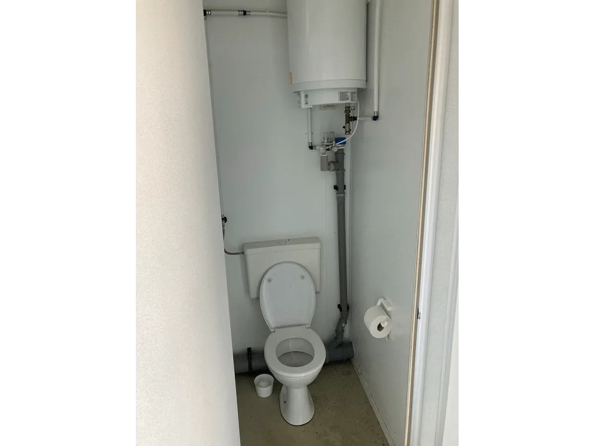 Innenansicht WC-Kabine mit Toilette und Wasseranschluss im Container