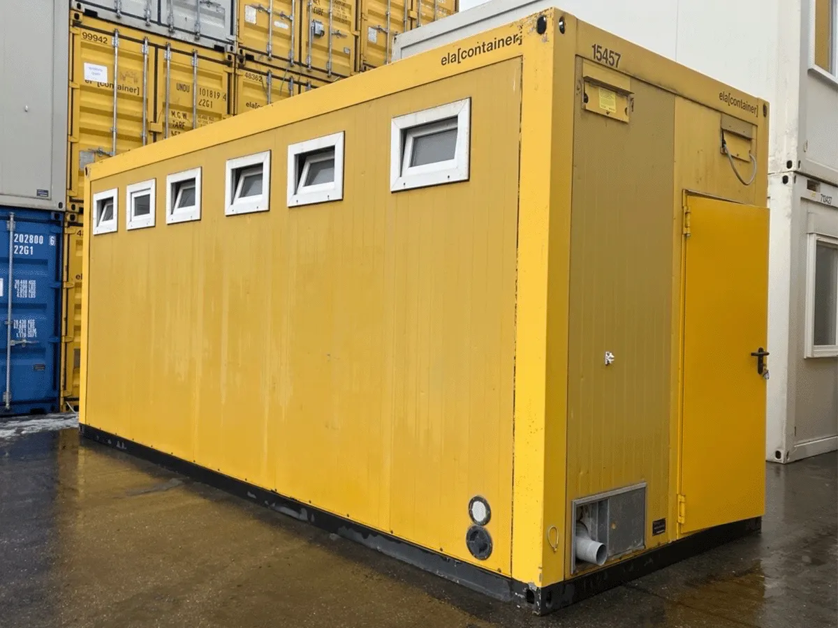 Gelber Sanitärcontainer mit Fenstern auf Baustelle, Außenansicht