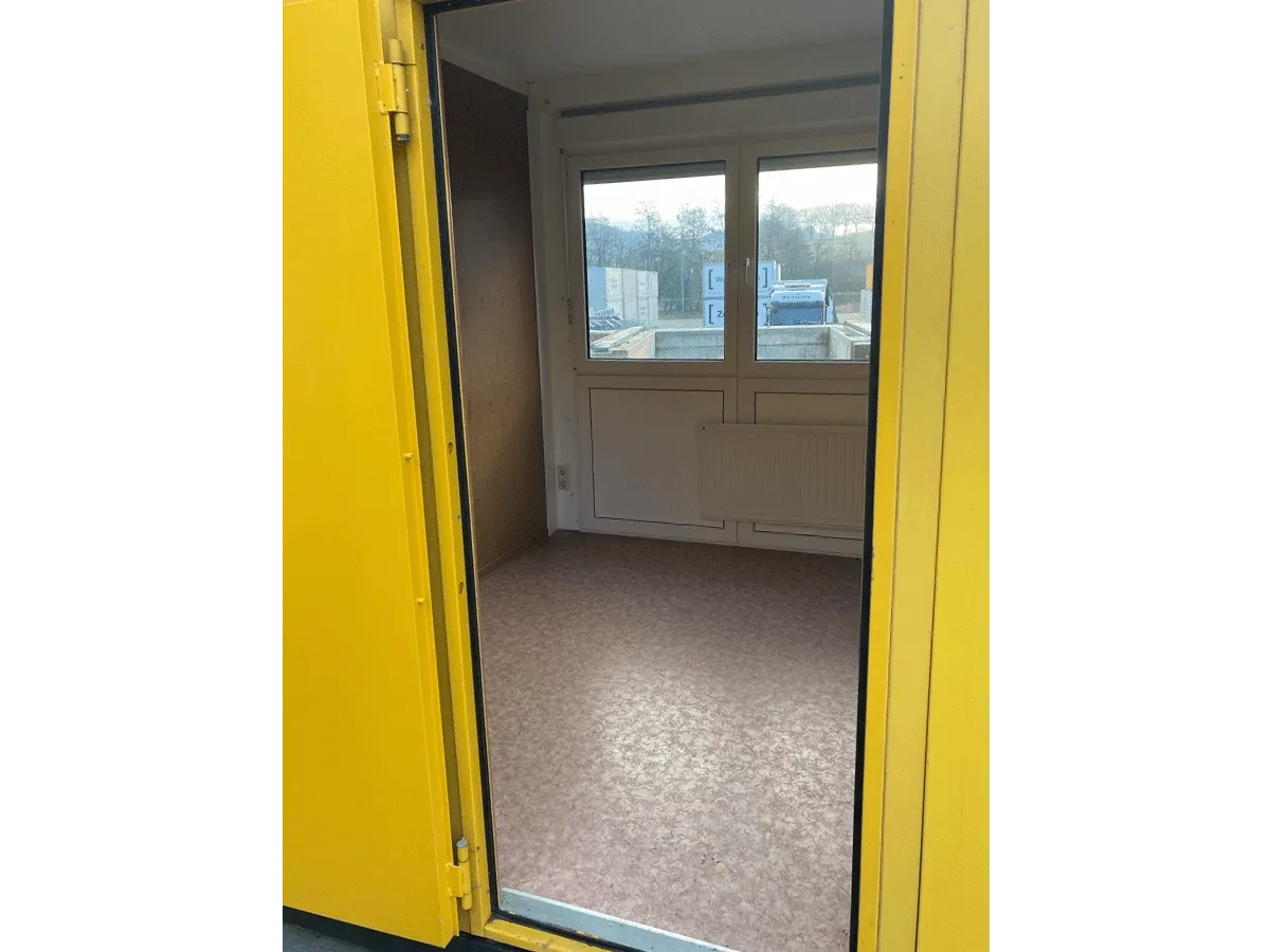 Gebrauchter 10 Fuß Bürocontainer Blick durch offene gelbe Tür auf Fenster und Vinylboden
