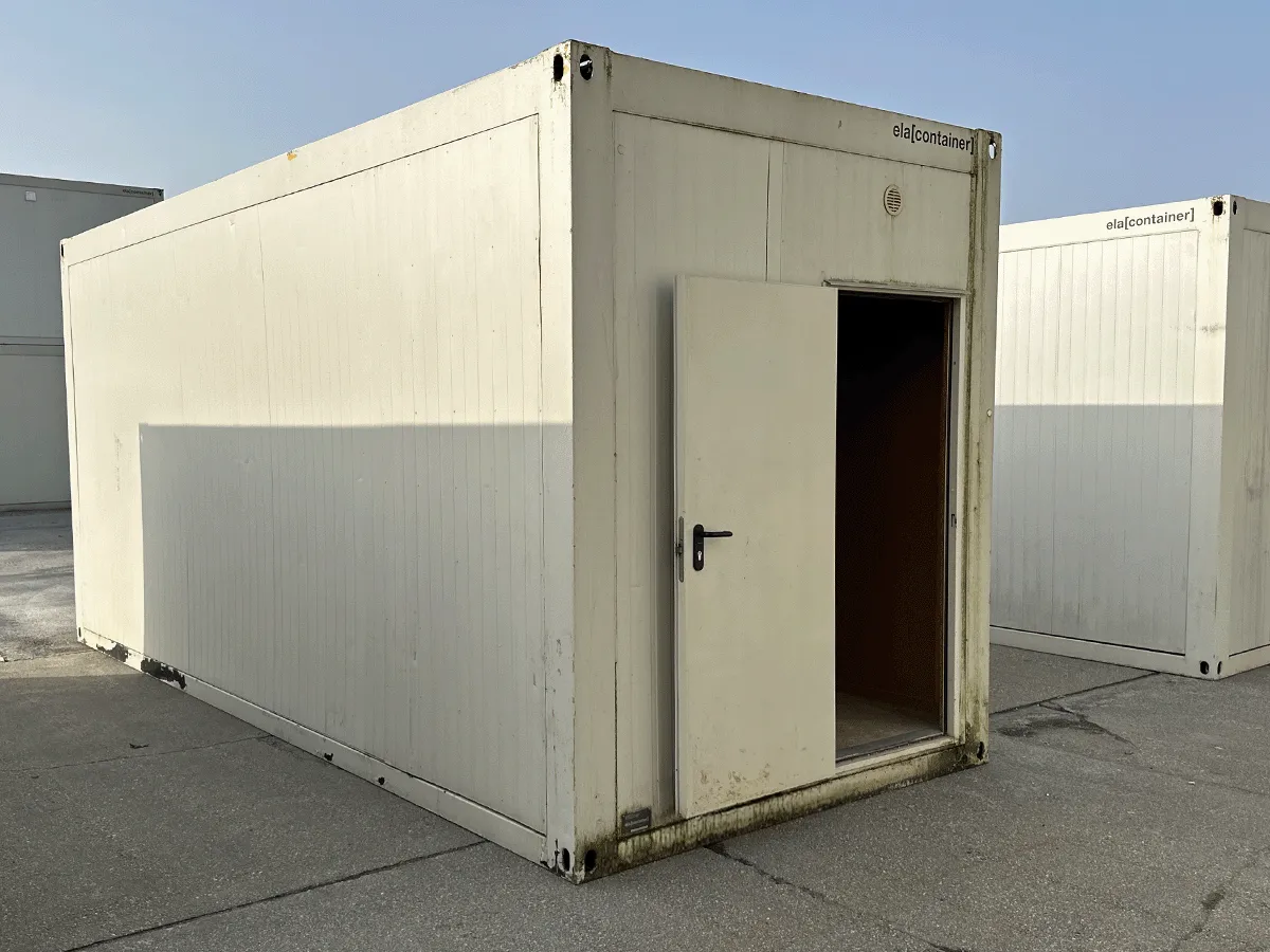 Seitenansicht des langen Paneels des gebrauchten grauen Bürocontainers, mit gelben Containern im Hintergrund.