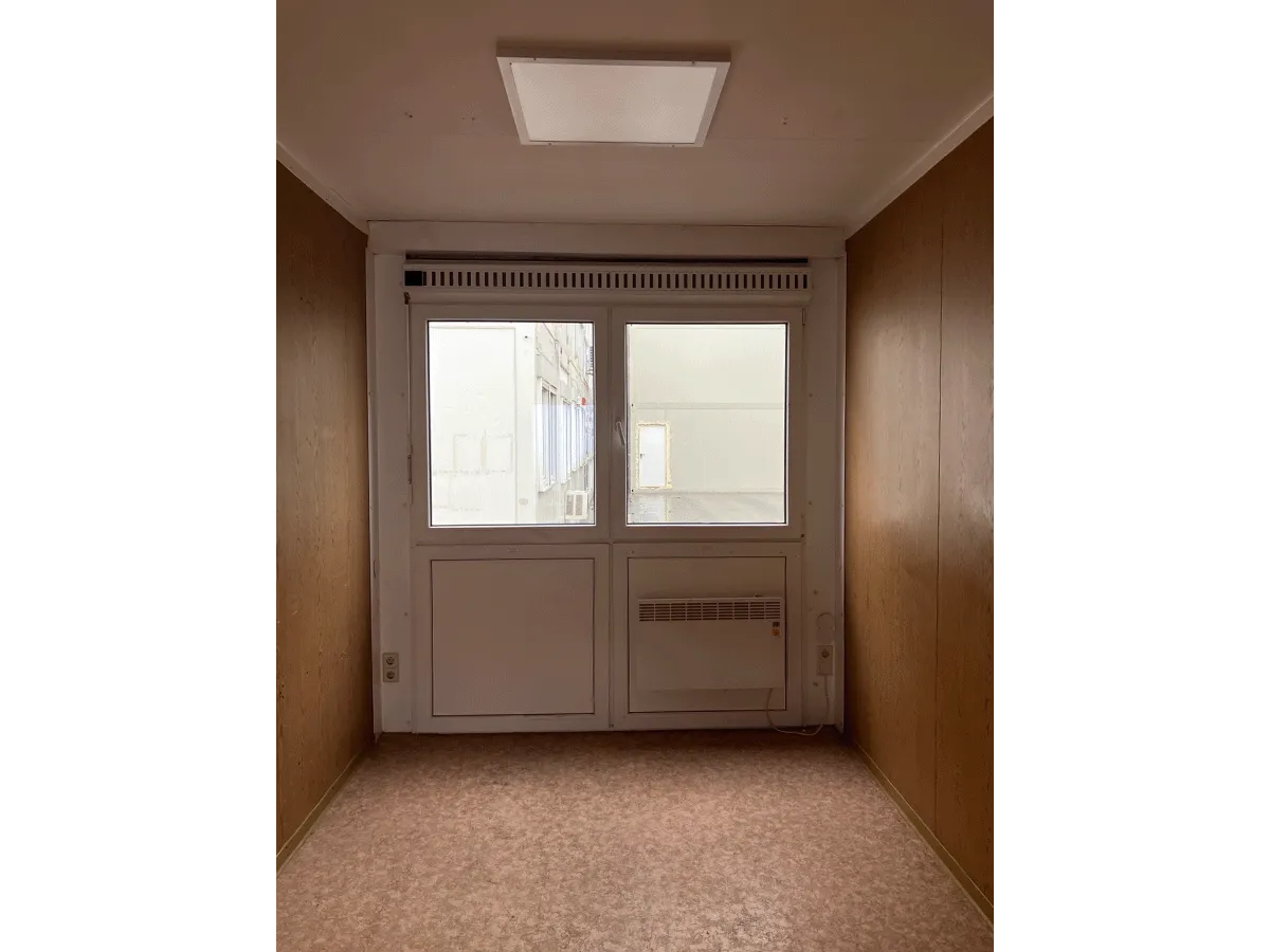 Gebrauchter 20 Fuß Bürocontainer Innenansicht mit großem Fenster, Konvektorheizung und Deckenleuchte – Blick zur Fensterseite