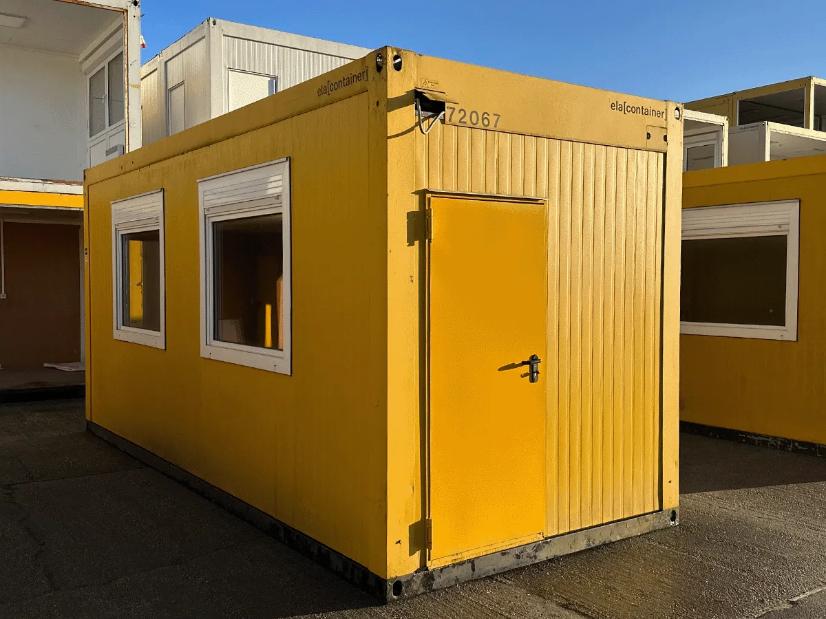 Gebrauchter 20 Fuß Bürocontainer gelb von ELA Container mit zwei Fenstern und Eingangstür – Frontansicht auf dem Containerplatz