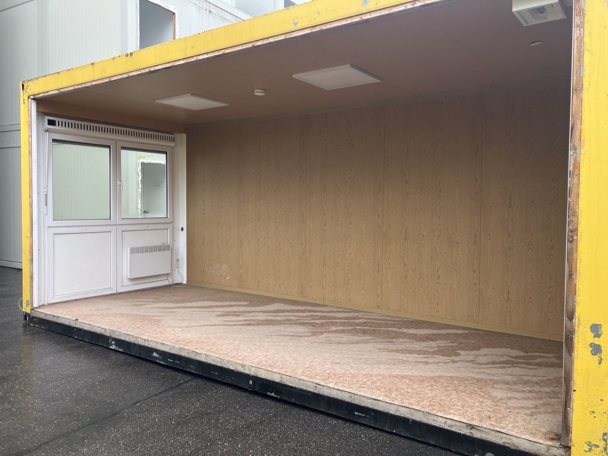 Gebrauchter 20 Fuß Bürocontainer gelb mit komplett offener Seitenfront, Glastür und Heizkörper – Außenansicht frontal